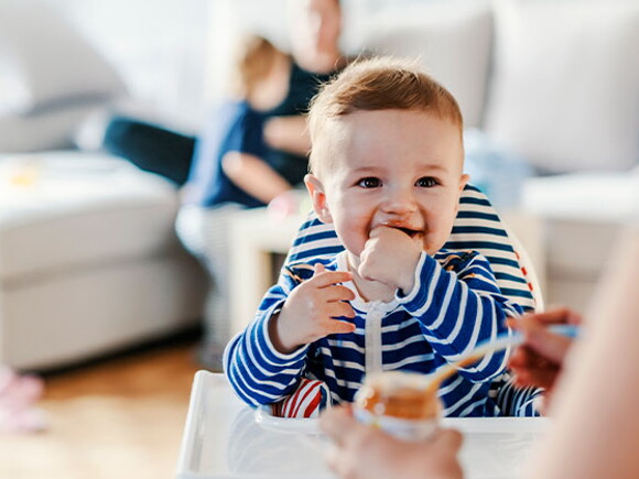 Bebé en su silla comiendo alimentos sólidos