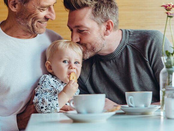 Niña comiendo galletas para bebés con su papá y abuelo