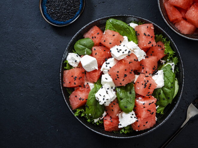 Un bowl que contiene cubos de sandía, espinacas y queso