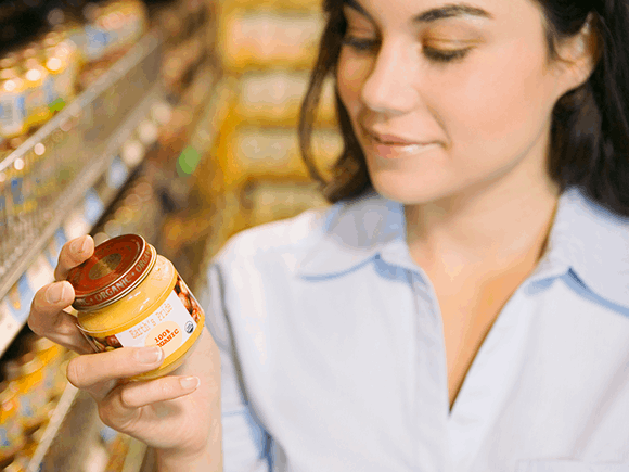 Mujer leyendo etiqueta nutricional con un frasco de colado para bebes