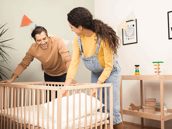 Un hombre y una mujer preparan la cuna del bebe