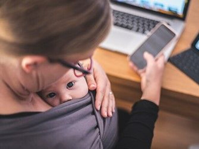 madre trabajando con su hijo en brazos