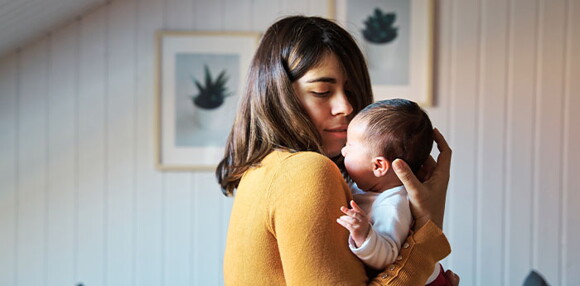 Mamá cargando a su bebé de un mes.